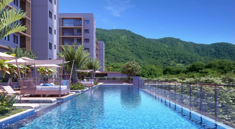 Piscina ao ar livre com espreguiçadeiras, guarda-sóis e vista para área verde e montanhas.